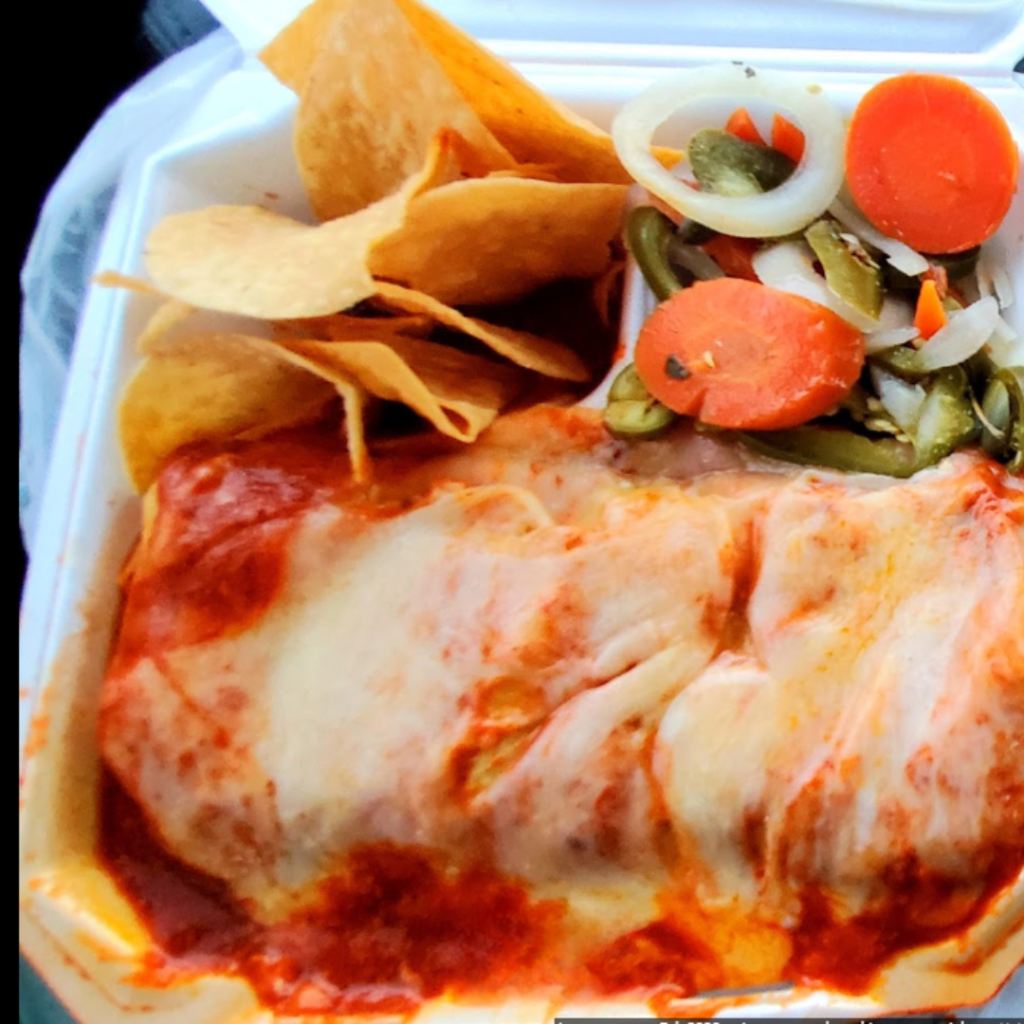 A scrumptious wet burrito meal from Taqueria Los Compadres, smothered in a savory sauce, accompanied by crispy tortilla chips and colorful pickled vegetables, served in a take-out container.